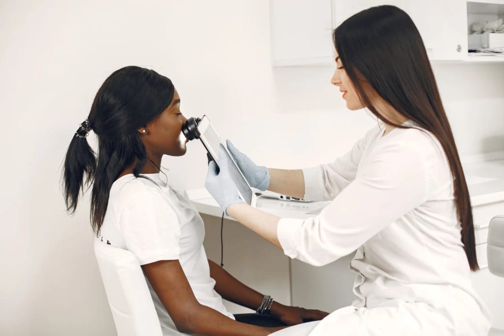 Dermatologinja dermatoskopom pregledava kožu pacijentice u ordinaciji