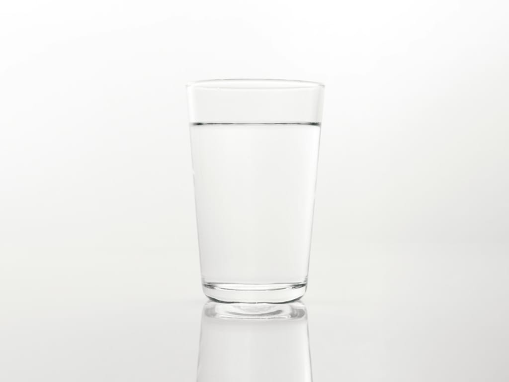 Čaša bistre vode na bijeloj podlozi